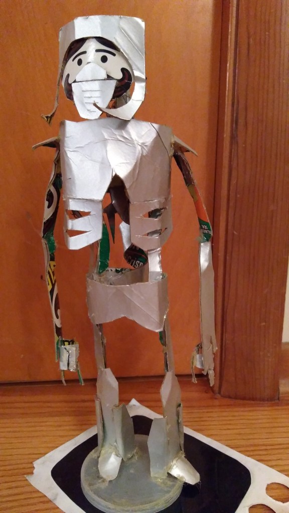 A skeletal sculpture made out of a single Pringles can and hot glue. The subject is an outer-space warrior naturalist/soldier with a heart of shrapnel and a corkscrew spinal cord. The cartoon face printed on a Pringles can is used as the sculpture's face, obscured by breathing-mask armor